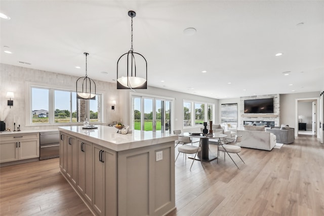 kitchen featuring a kitchen island, hanging light fixtures, a wealth of natural light, and light hardwood / wood-style flooring