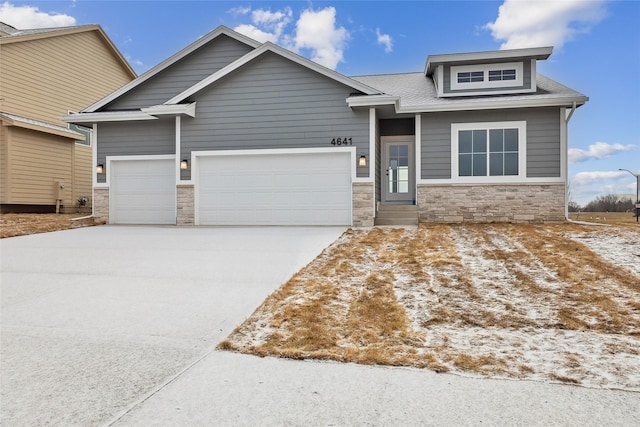 view of front of home with an attached garage, stone siding, and concrete driveway