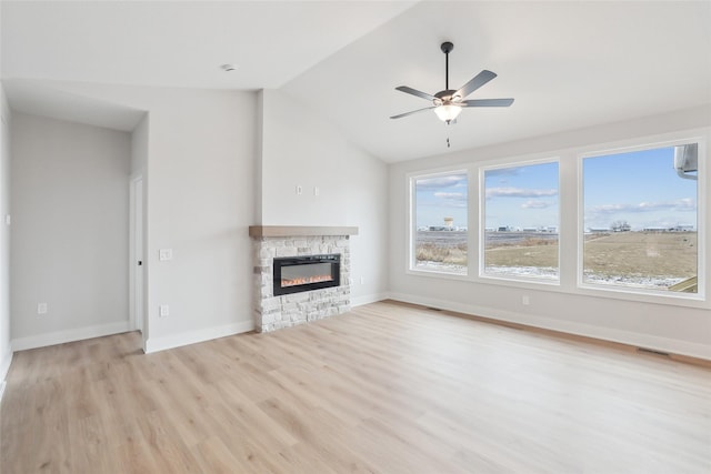 unfurnished living room featuring light hardwood / wood-style floors, a stone fireplace, ceiling fan, and lofted ceiling