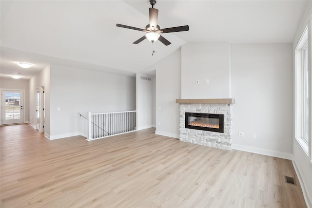 unfurnished living room featuring ceiling fan, lofted ceiling, a fireplace, and light hardwood / wood-style flooring