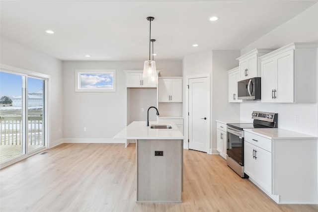 kitchen with white cabinetry, sink, pendant lighting, a kitchen island with sink, and appliances with stainless steel finishes