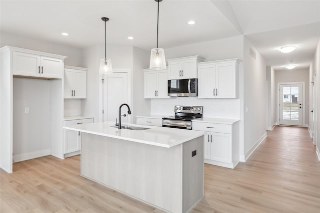 kitchen with sink, stainless steel appliances, an island with sink, pendant lighting, and white cabinets