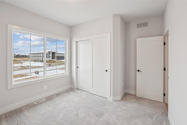 unfurnished bedroom featuring light colored carpet and a closet