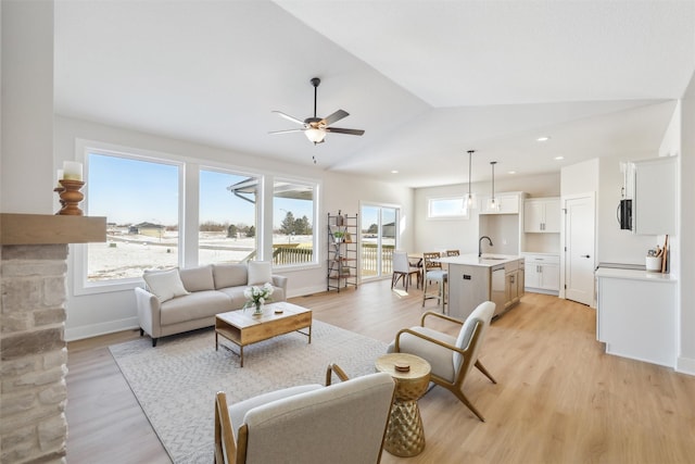 living area featuring lofted ceiling, light wood-type flooring, and baseboards