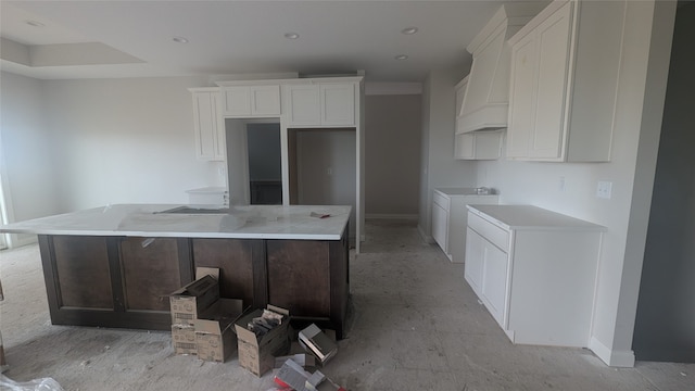 kitchen with washing machine and dryer, white cabinetry, a kitchen island, and light stone counters