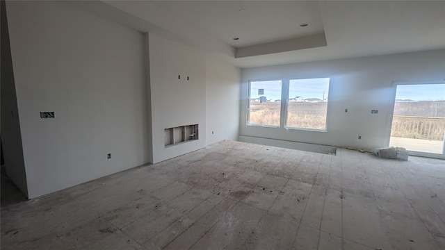 unfurnished living room featuring light wood-type flooring, a fireplace, and a tray ceiling