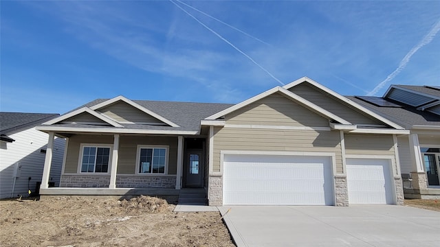 craftsman-style home with stone siding, a porch, concrete driveway, and a garage