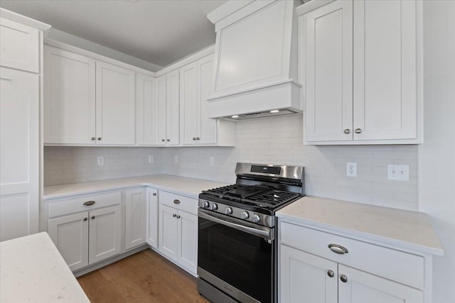 kitchen featuring gas range, dark wood-type flooring, decorative backsplash, and white cabinets