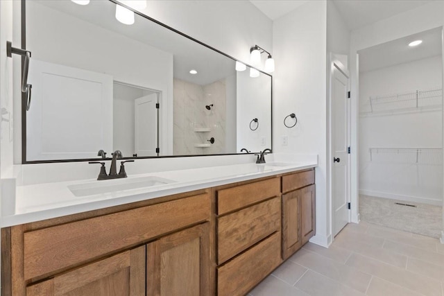 bathroom with tile patterned flooring, vanity, and tiled shower