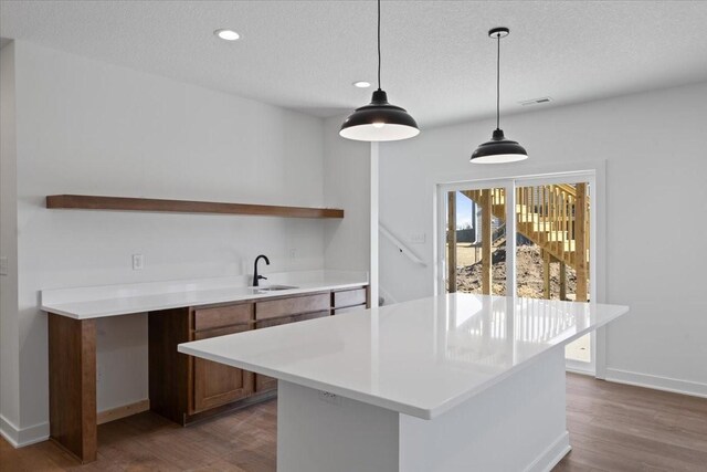 kitchen featuring pendant lighting, sink, a center island, and a textured ceiling