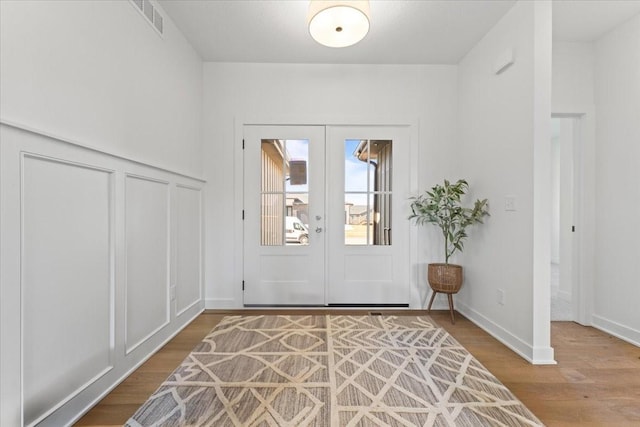 foyer with french doors, wood finished floors, visible vents, and baseboards