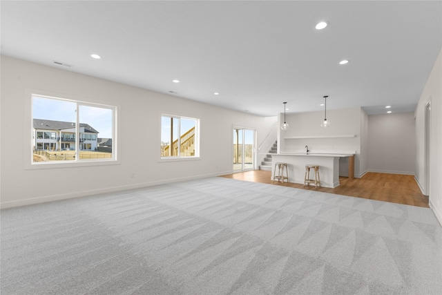 unfurnished living room featuring light colored carpet and plenty of natural light