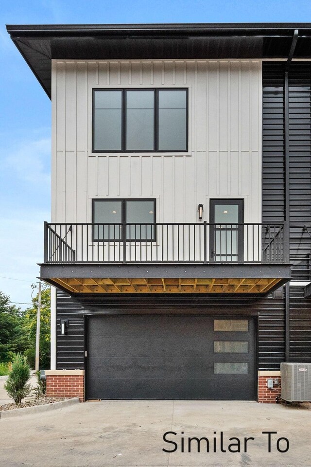 view of front facade with a balcony, a garage, and central AC unit