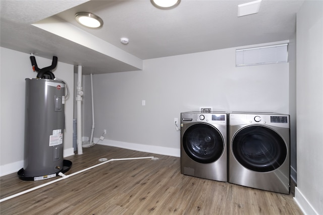 clothes washing area featuring hardwood / wood-style flooring, washing machine and dryer, and electric water heater