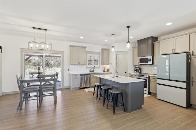kitchen featuring a sink, a kitchen island, light wood finished floors, a breakfast bar area, and stainless steel appliances