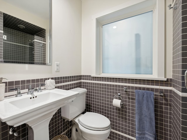 bathroom with sink, tile walls, and toilet