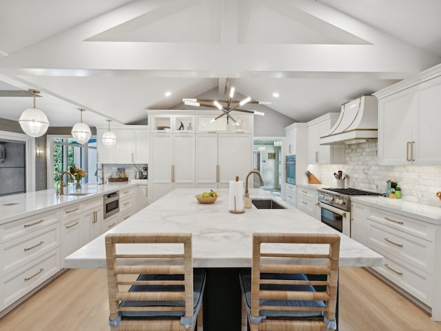 kitchen featuring appliances with stainless steel finishes, white cabinetry, a spacious island, and sink