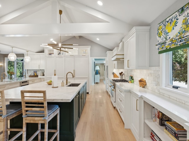 kitchen with sink, hanging light fixtures, stainless steel stove, decorative backsplash, and white cabinets