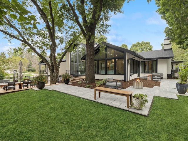 rear view of property with a sunroom, a patio, and a lawn