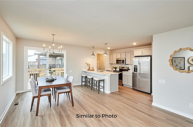 dining area featuring light wood-type flooring, sink, and an inviting chandelier