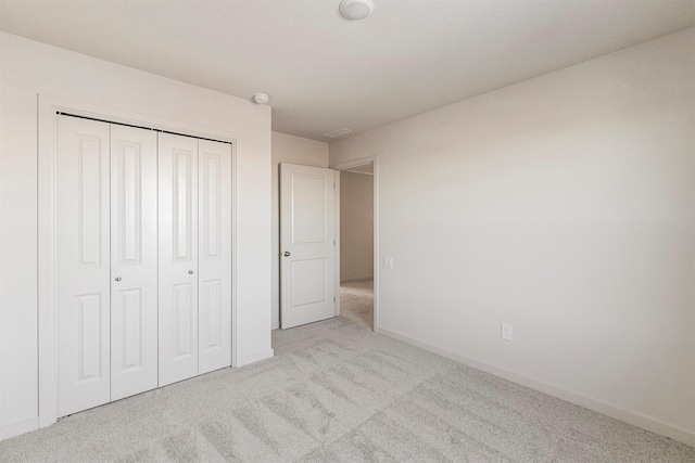 unfurnished bedroom with light carpet and a closet