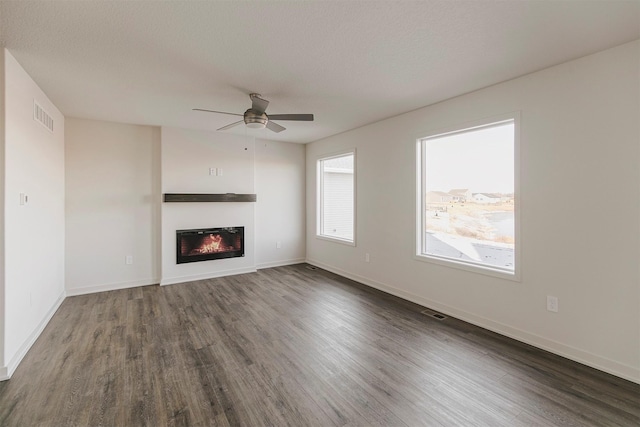 unfurnished living room with dark wood-type flooring, ceiling fan, and a textured ceiling