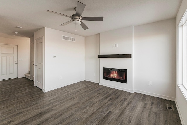 unfurnished living room featuring dark wood-type flooring, ceiling fan, and a textured ceiling