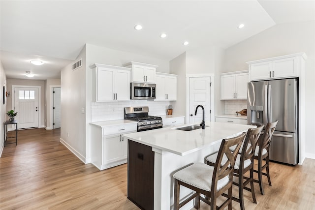 kitchen with appliances with stainless steel finishes, an island with sink, white cabinetry, and sink