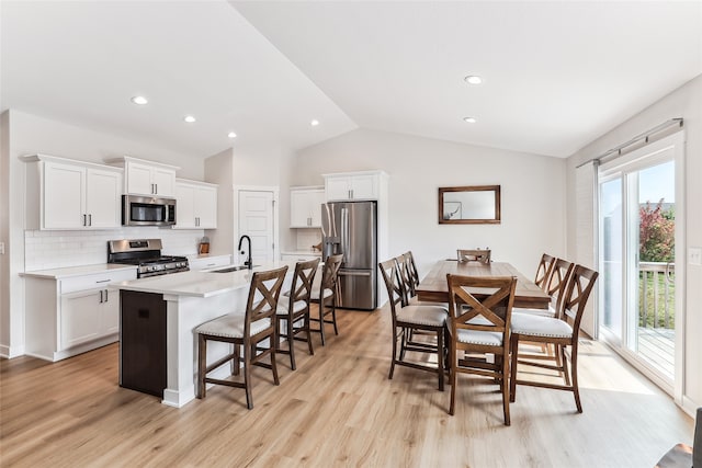 kitchen featuring sink, stainless steel appliances, lofted ceiling, a kitchen island with sink, and white cabinets