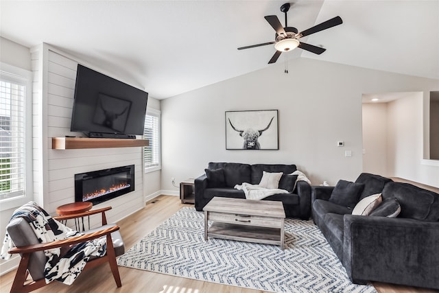 living room with ceiling fan, light hardwood / wood-style floors, lofted ceiling, and a fireplace