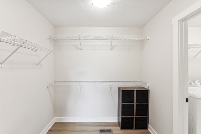 walk in closet with hardwood / wood-style floors and separate washer and dryer