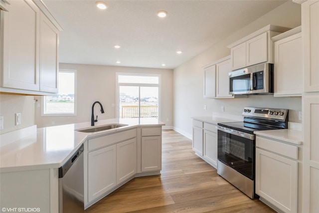 1109 Mulberry Dr NW, Bondurant, IA 50035 - kitchen with a peninsula, a sink, light wood-type flooring, light countertops, and appliances with stainless steel finishes