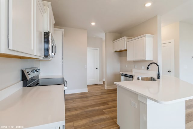 kitchen with white cabinetry, sink, kitchen peninsula, appliances with stainless steel finishes, and light wood-type flooring