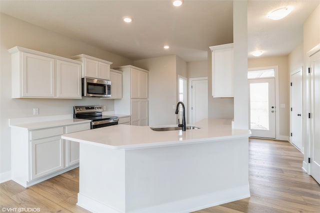 kitchen with sink, white cabinets, stainless steel appliances, and light hardwood / wood-style flooring