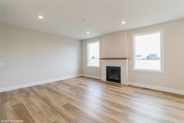1109 Mulberry Dr NW, Bondurant, IA 50035 - unfurnished living room with light wood-type flooring, a glass covered fireplace, recessed lighting, and visible vents