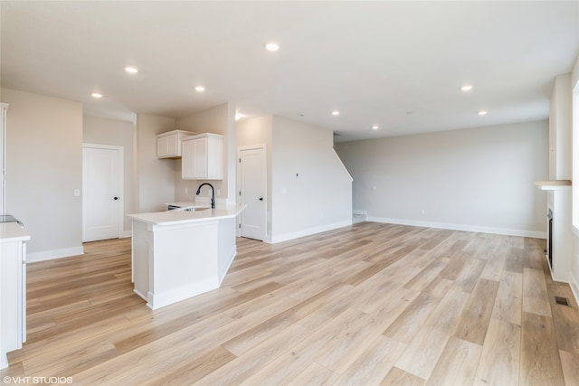 kitchen featuring sink, white cabinetry, light hardwood / wood-style flooring, and an island with sink