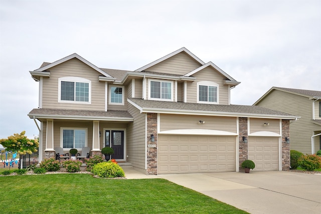 view of front of property with covered porch, a front yard, and a garage