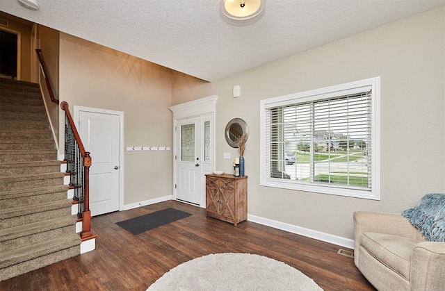 entryway with dark wood-type flooring and a textured ceiling