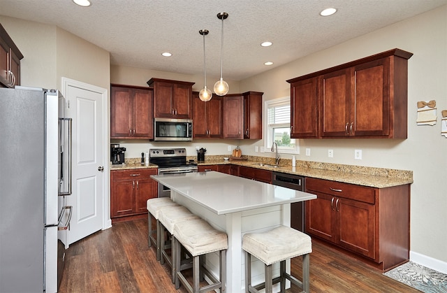 kitchen featuring appliances with stainless steel finishes, a textured ceiling, dark hardwood / wood-style flooring, and decorative light fixtures