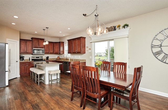 dining area with a textured ceiling, a chandelier, sink, and dark hardwood / wood-style floors