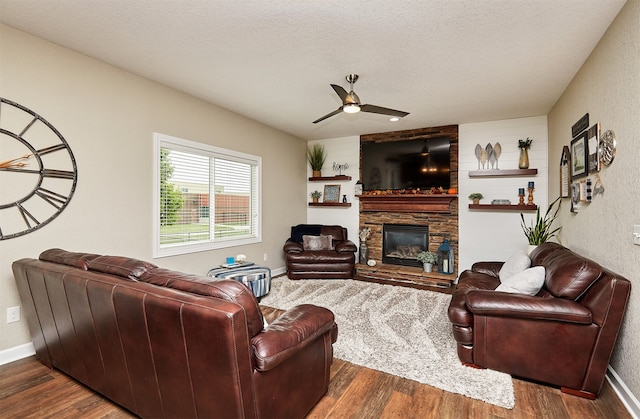 living room with a fireplace, dark wood-type flooring, a textured ceiling, and ceiling fan