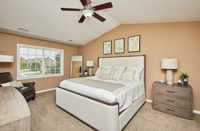 bedroom with light carpet, lofted ceiling, ceiling fan, and a textured ceiling