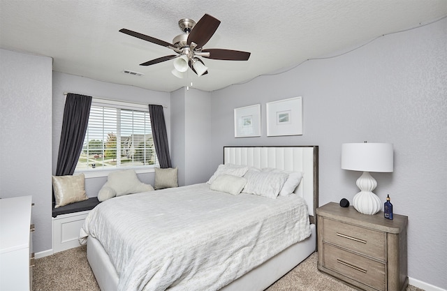 bedroom with a textured ceiling, ceiling fan, and light carpet