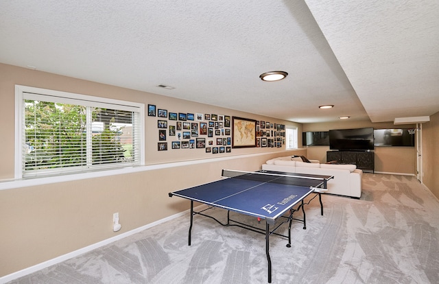 recreation room with a textured ceiling and light colored carpet