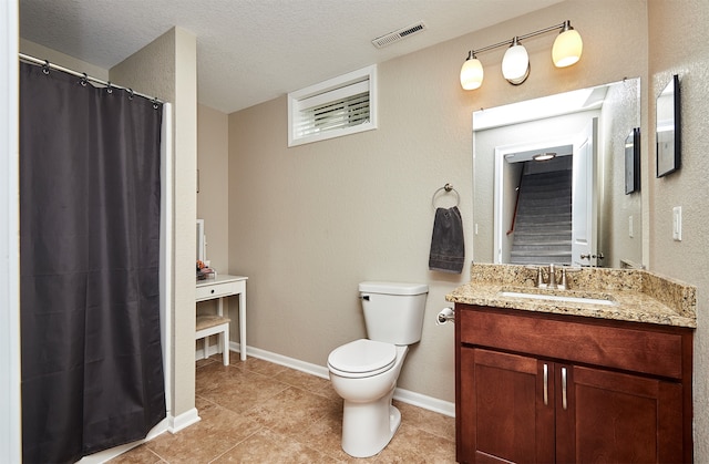 bathroom featuring tile patterned floors, toilet, a textured ceiling, and vanity