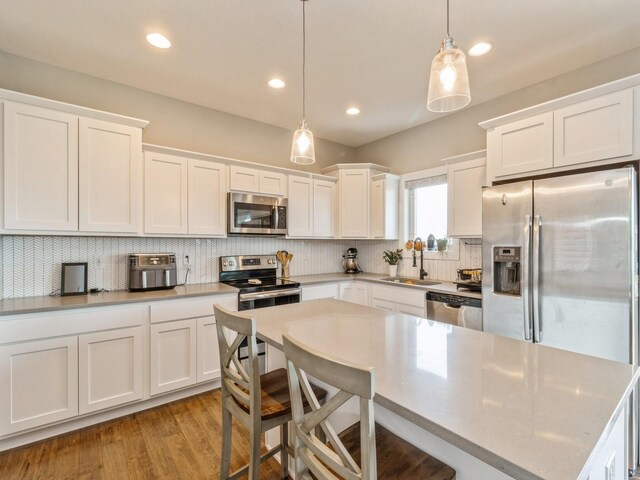 1401 S 10th St, Adel, IA 50003 - kitchen with stainless steel appliances, a sink, white cabinets, decorative backsplash, and decorative light fixtures