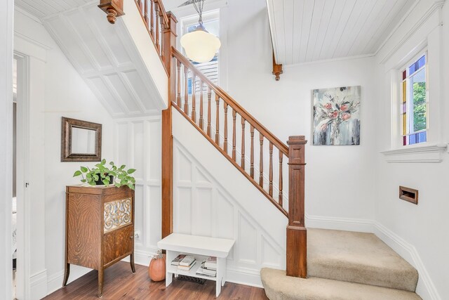 stairway featuring vaulted ceiling, ornamental molding, and hardwood / wood-style flooring