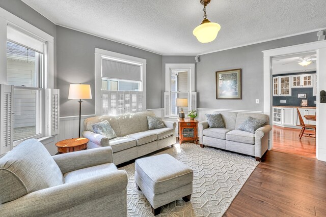 living room with hardwood / wood-style floors, ceiling fan, a wealth of natural light, and a textured ceiling