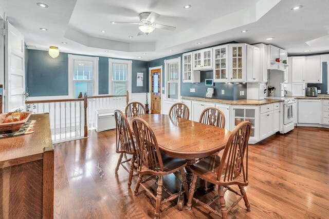 dining room with a raised ceiling, ceiling fan, and hardwood / wood-style floors