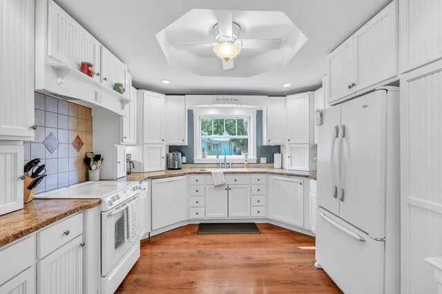 kitchen featuring white appliances, a tray ceiling, light hardwood / wood-style floors, white cabinetry, and ceiling fan